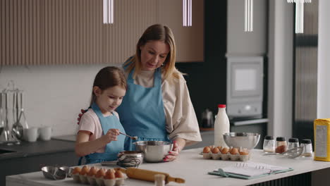 cute-child-girl-is-helping-to-her-mother-in-kitchen-mom-and-daughter-are-cooking-together